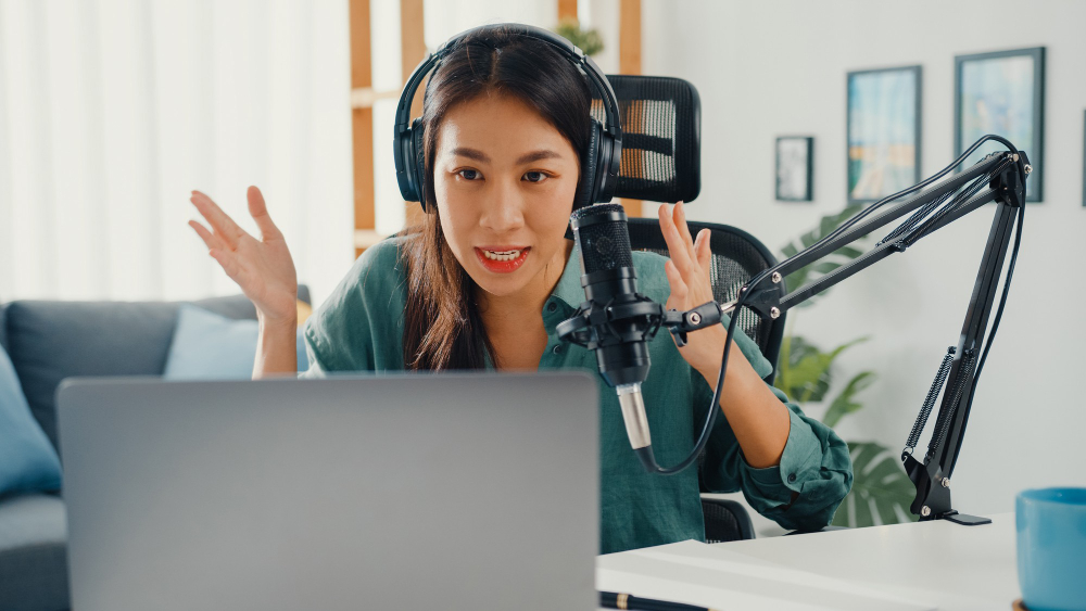 A Girl Recording a Podcast on Her Laptop Computer With Headphones and Microphone 